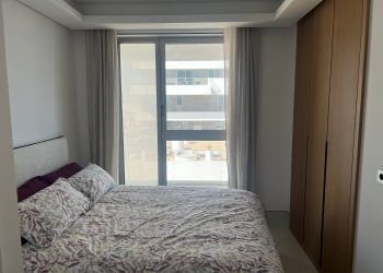 Second bedroom with built in wardrobes, vanity desk, and sea view